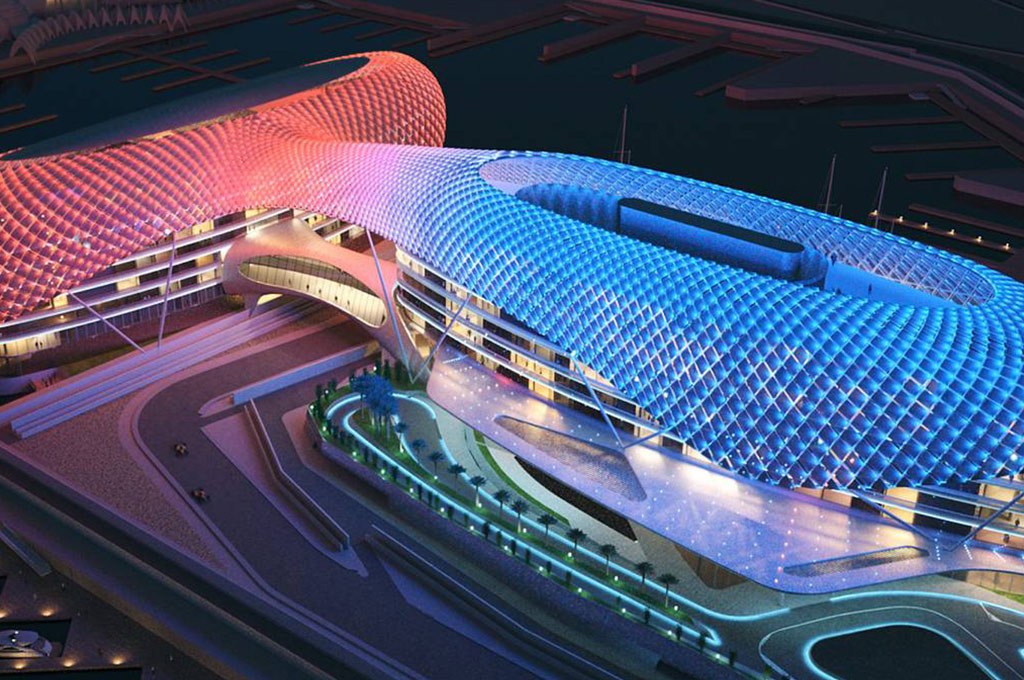 Architectural night view of the Yas Hotel in Abu Dhabi with its iconic LED grid shell, illuminating the skyline and Formula 1 racetrack at Yas Marina Circuit